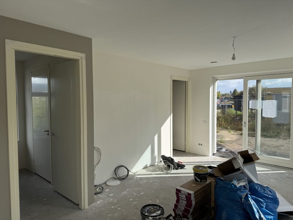 Net opgeleverde woonkamer met kale betonvloer en een schuifpui