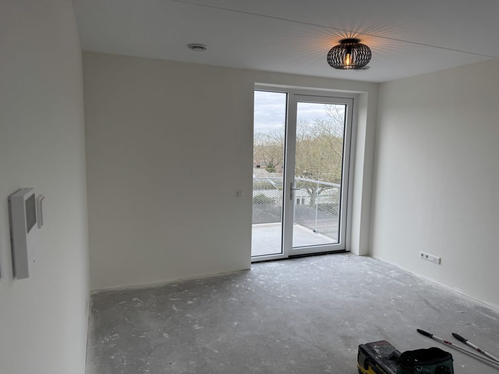 Kale kamer van een net opgeleverd appartement met balkondeuren